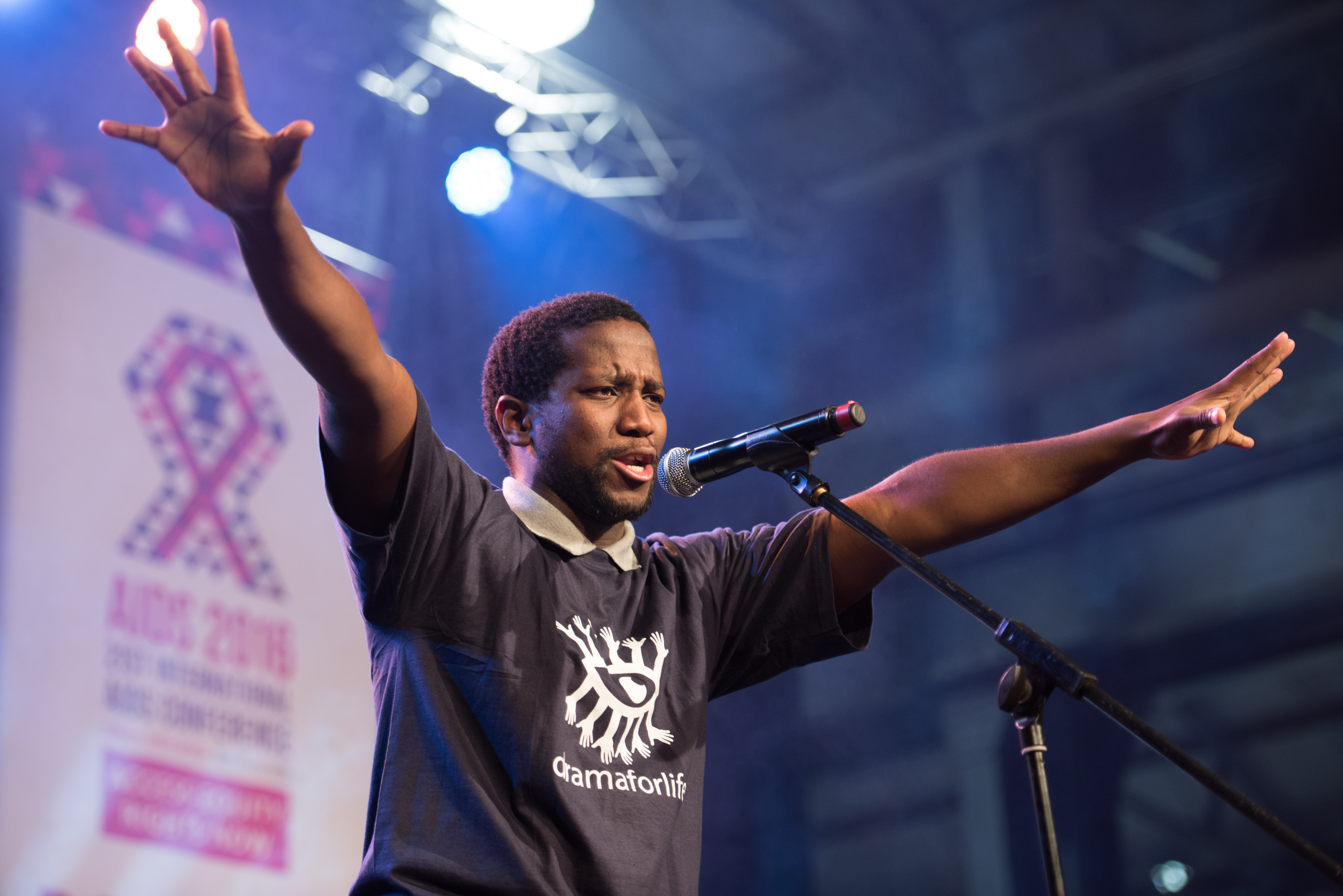 man speaking on a stage at a conference holding his arms out 