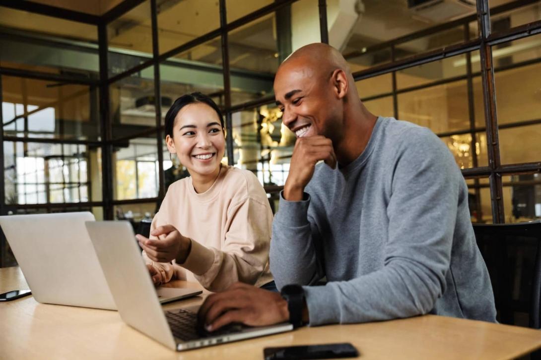 Two people talking in front of a laptop in an office