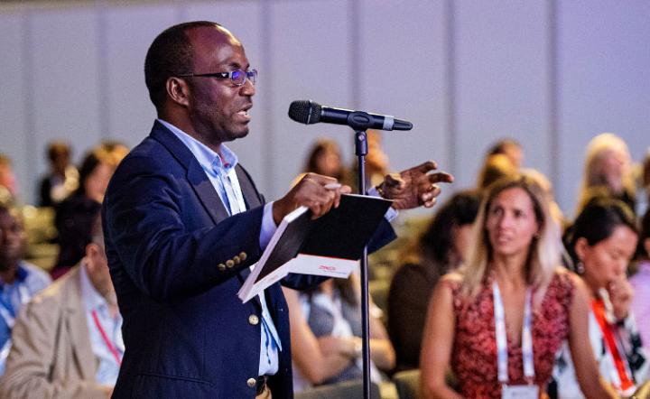 man speaking at microphone at conference