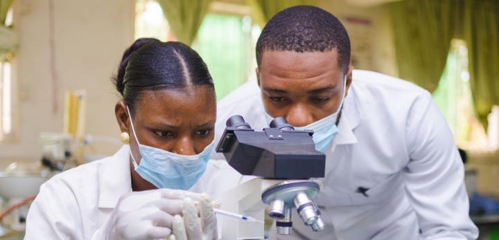 two technicians working with a microscope in a lab